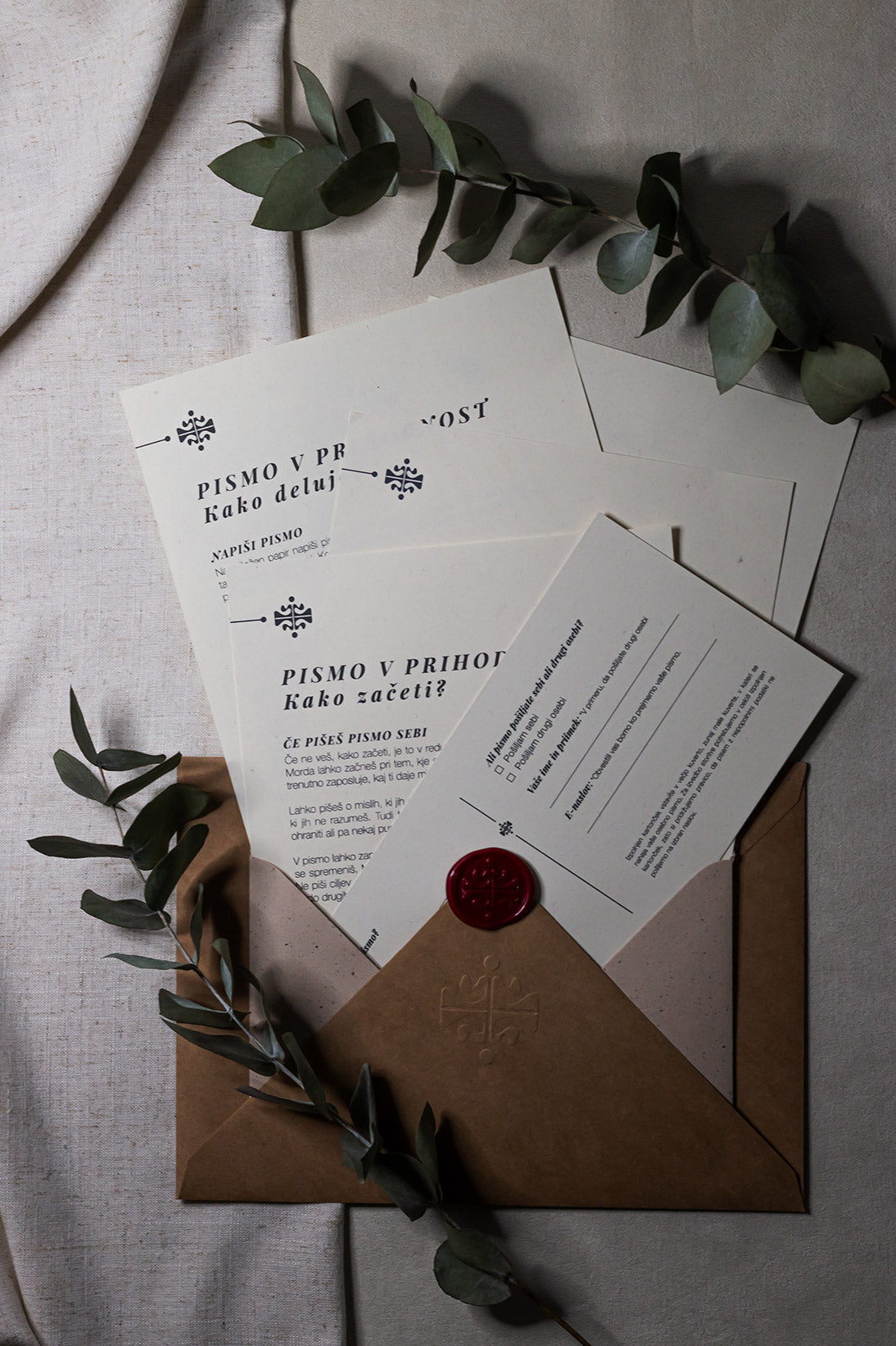 Prikaz celotne vsebine paketa Pismo v prihodnost blagovne znamke Letera. Komplet vključuje navodila za uporabo, kartico z idejami za pisanje, obrazec za naslovnika ter kraft in zaščitne ovojnice z voščenim pečatom.