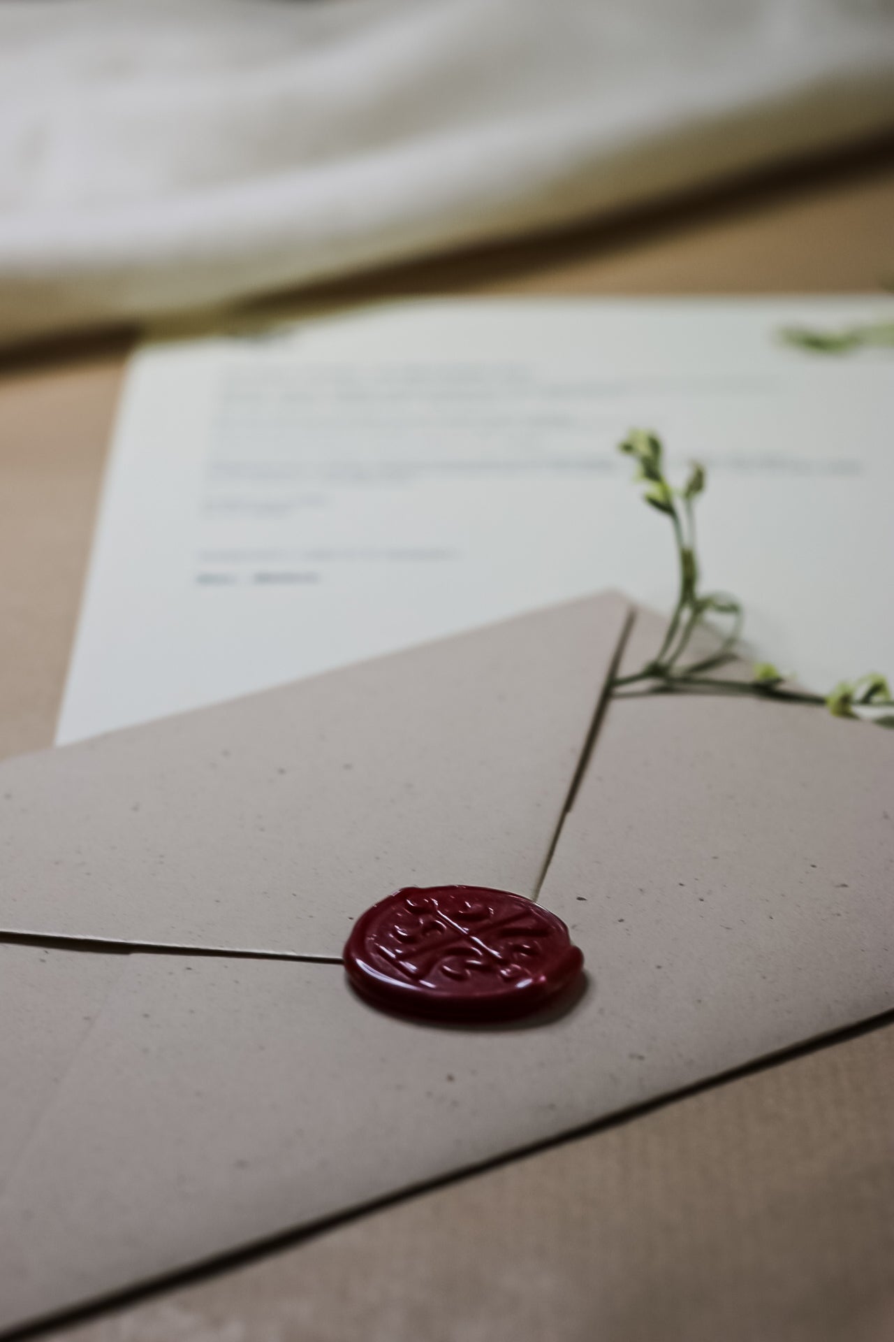 Fokus na rdečem voščenem pečatu na zaprti kraft ovojnici. Prikaz varnega shranjevanja in zasebnosti vsebine pisma v prihodnost blagovne znamke Letera. Simbolika varovanja skrivnosti do trenutka odprtja.