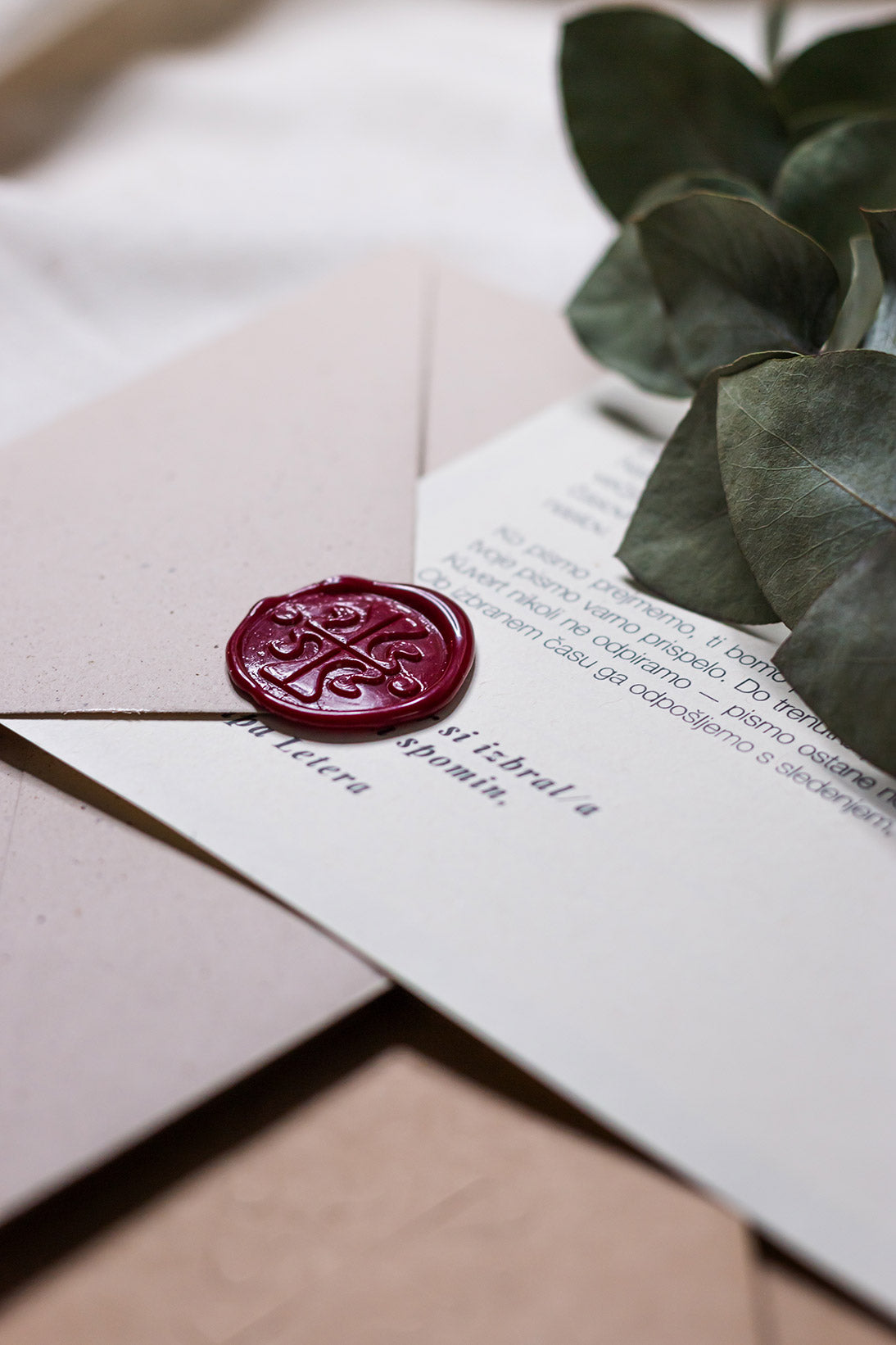 Bližnji posnetek (makro) rdečega voščenega pečata z vtisnjenim logotipom Letera. Detajl prikazuje kakovost ročne izdelave in teksturo papirja pri setu Pismo v prihodnost.